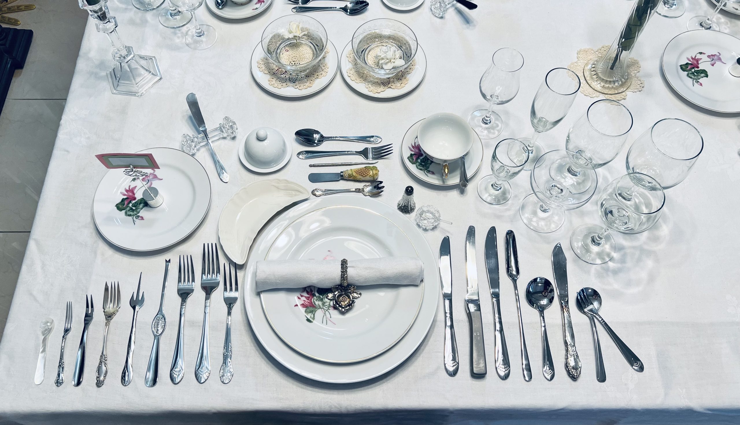 Overhead view of a formal table setting with plates, folded napkin, rows of cutlery and several glasses