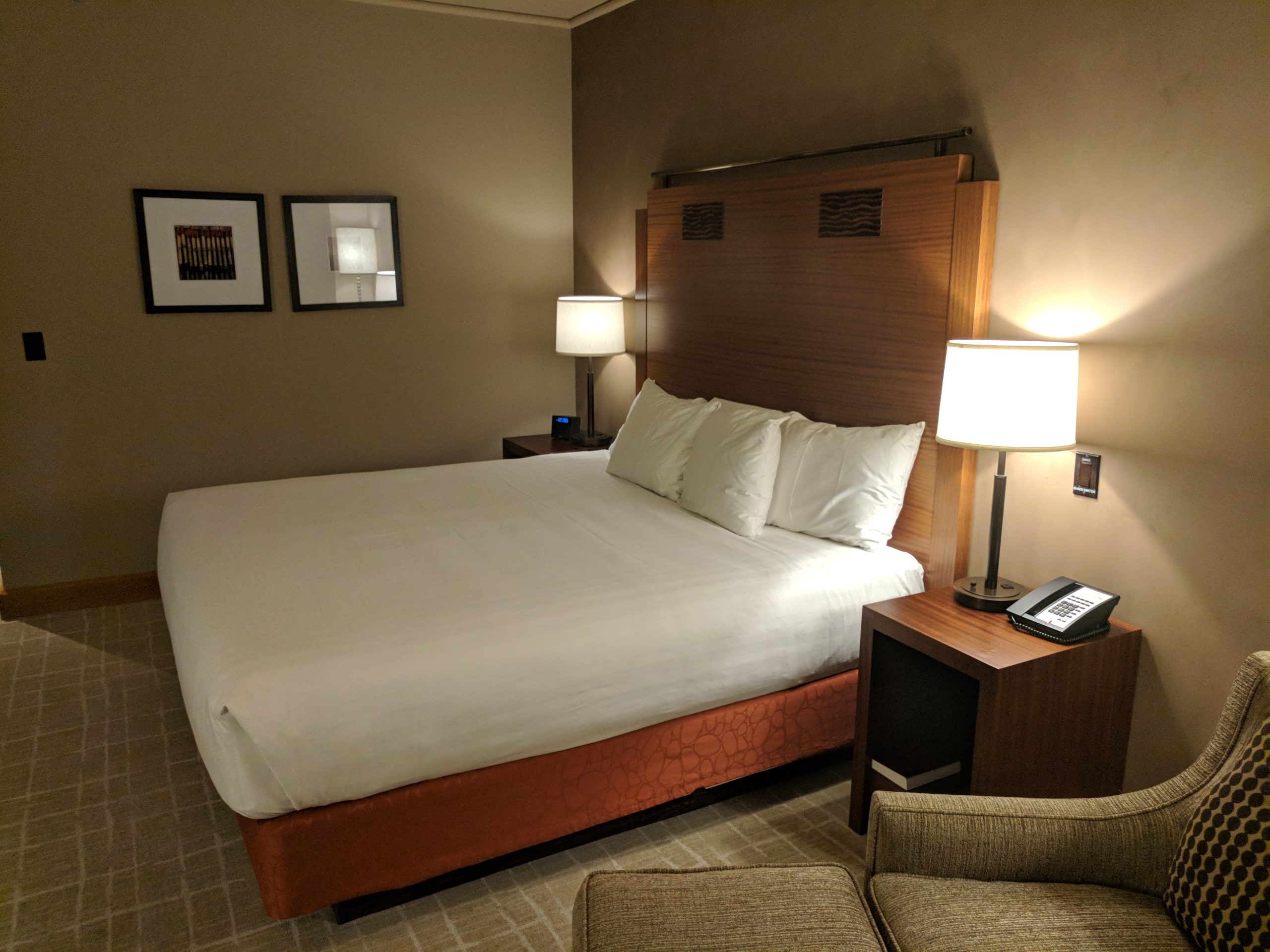 Neatly made bed with white pillows and two bedside lamps in a dim, quiet bedroom
