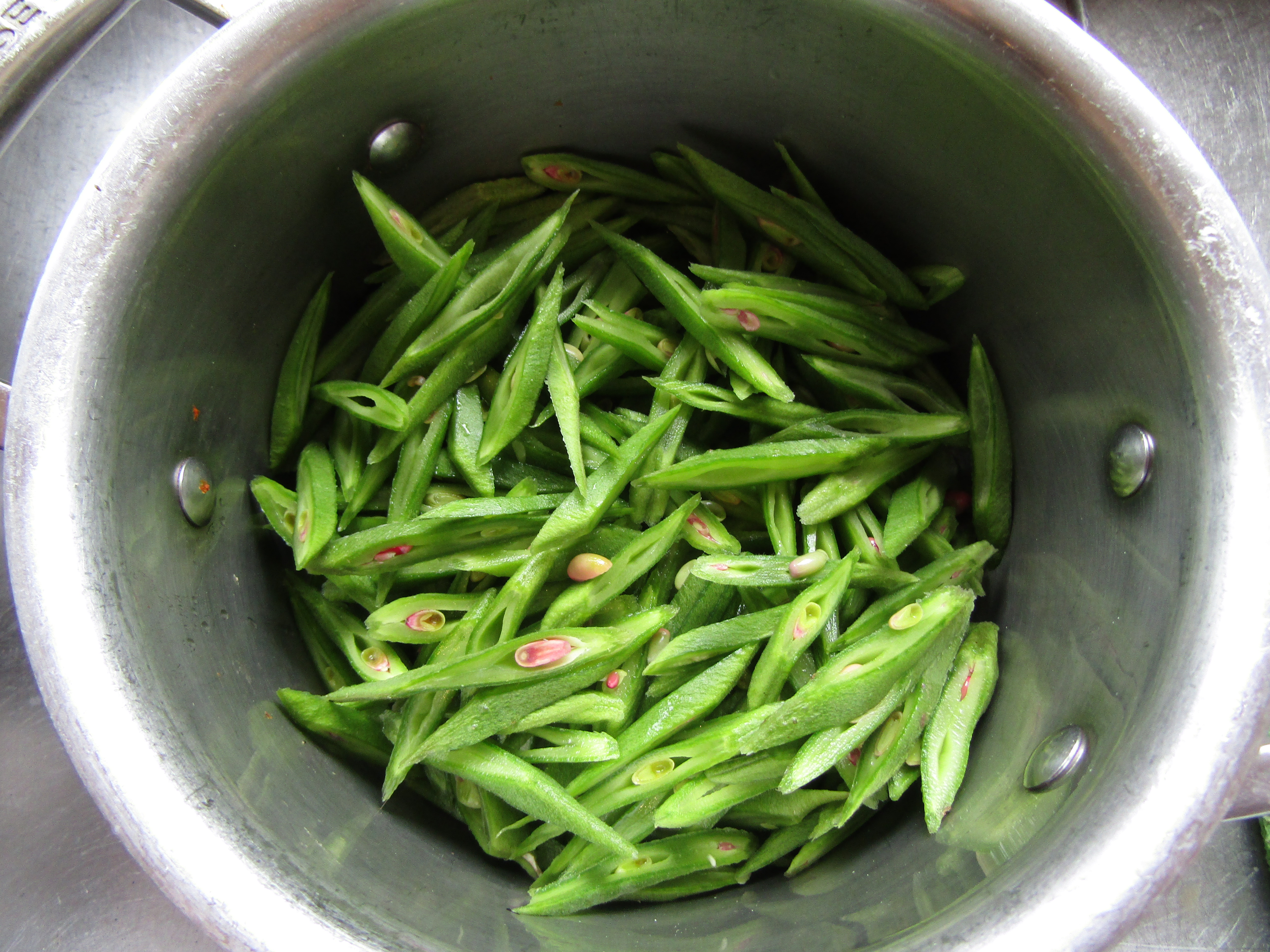 Trimmed green runner beans prepped and waiting in a stainless steel saucepan