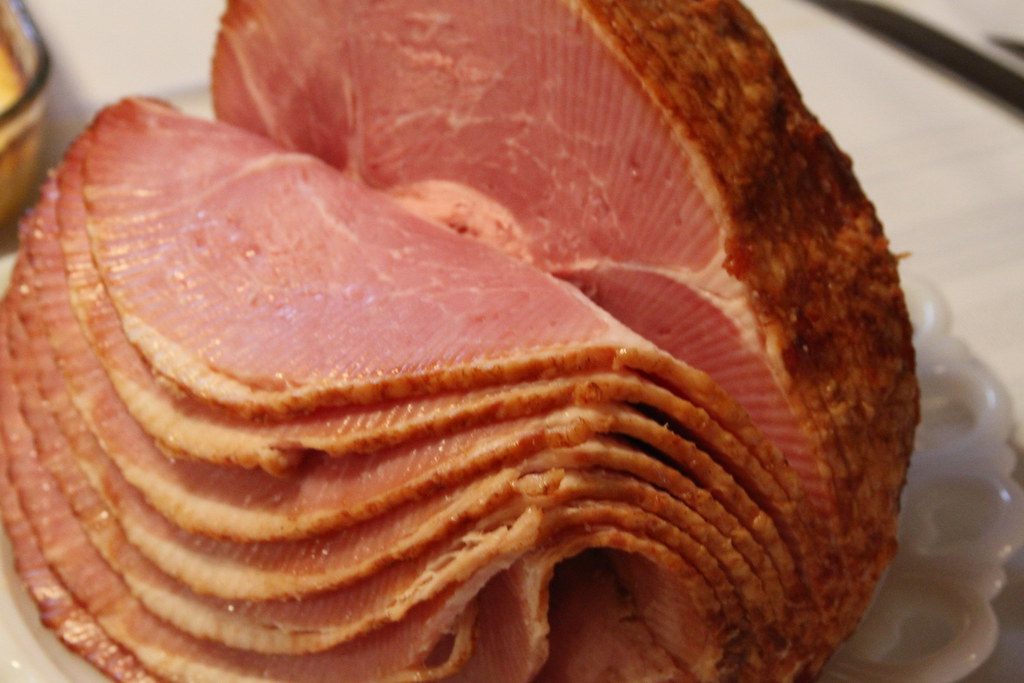 Spiral-cut glazed ham with a golden spiced sugar crust on a white serving plate